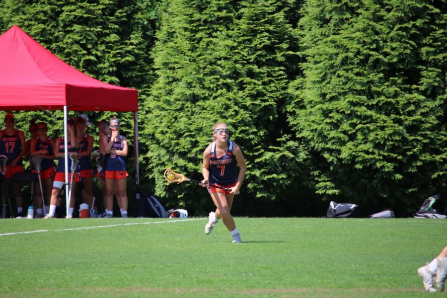 Kate Marano jumps onto the field playing lacrosse with her team. 