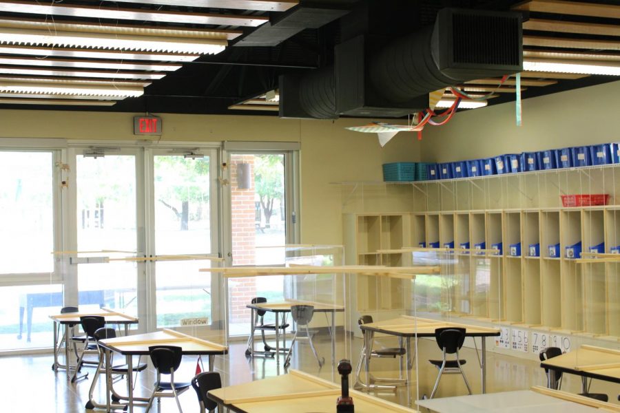 A classroom in the preschool has plexiglass barriers on each desk.