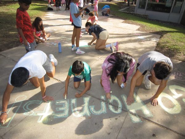 Students use chalk to draw encouraging messages for athletes participating in Homecoming athletic games. Photo courtesy of Gigi Melucci.